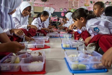 Gambar siswa menikmati makan siang gratis di kantin sekolah dengan suasana ceria